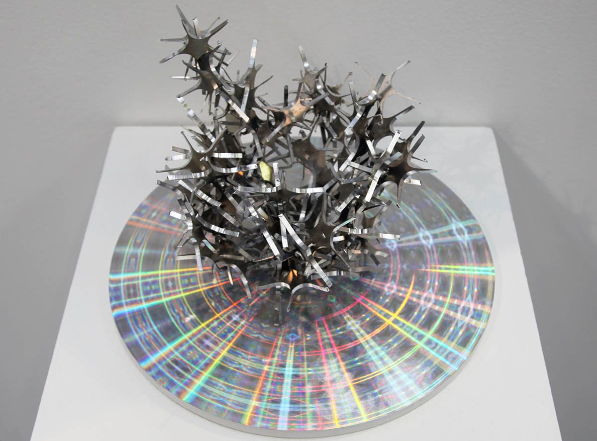 A metal sculpture of spikes on top of a cd.